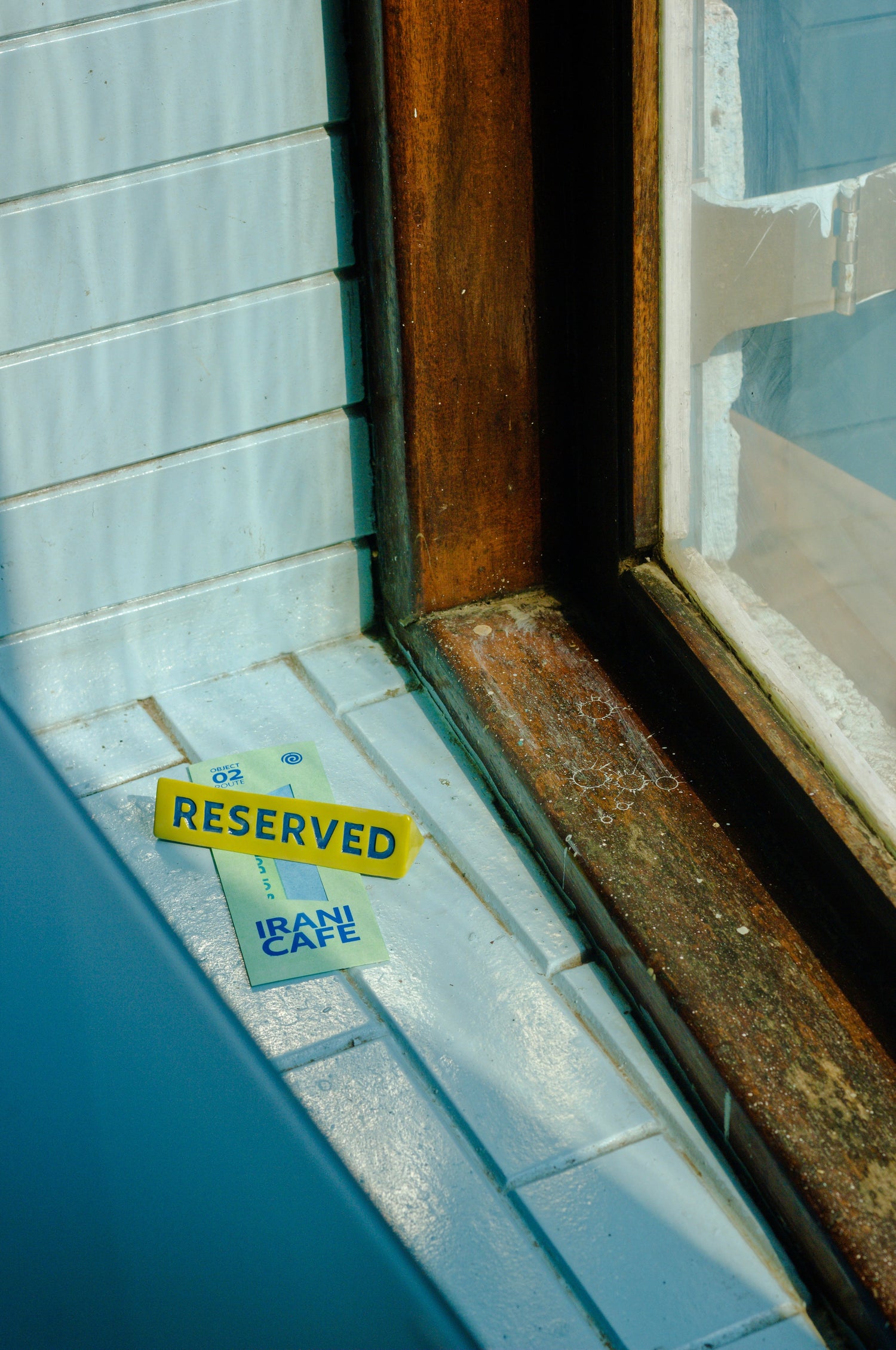 Reserved ceramic sign resting on the Irani Cafe window ledge